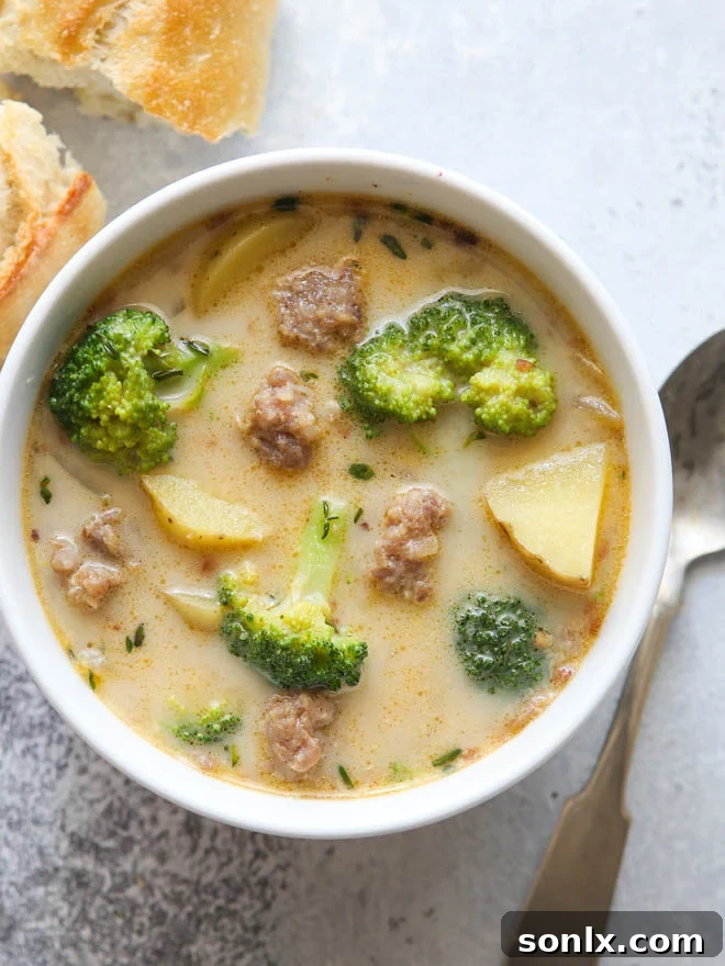A steaming bowl of hearty sausage, broccoli, and potato soup garnished with fresh herbs, ready to be enjoyed.