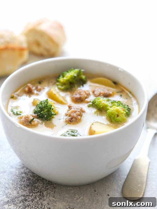 A vibrant and appetizing close-up of a bowl of sausage, broccoli, and potato soup, highlighting the fresh ingredients and creamy texture. Garnished with a sprig of fresh thyme, it exudes coziness and satisfaction.