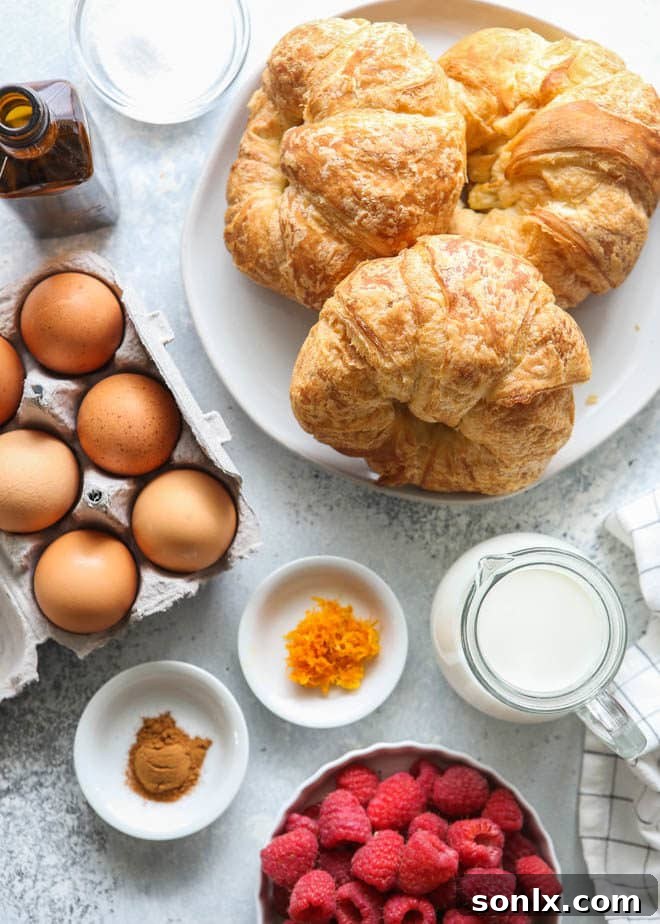 All the fresh ingredients laid out for making the best croissant French toast, including eggs, milk, sugar, vanilla, cinnamon, orange zest, and mini croissants