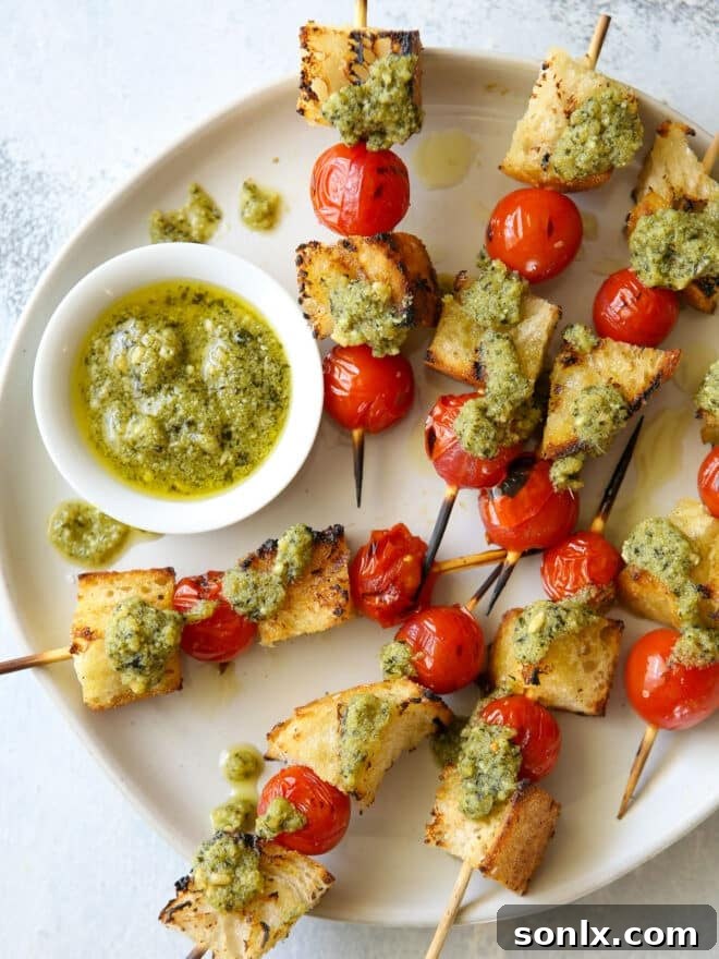 Beautifully arranged grilled bruschetta pesto skewers on a platter, showcasing toasted bread, vibrant cherry tomatoes, and fresh green pesto drizzle.
