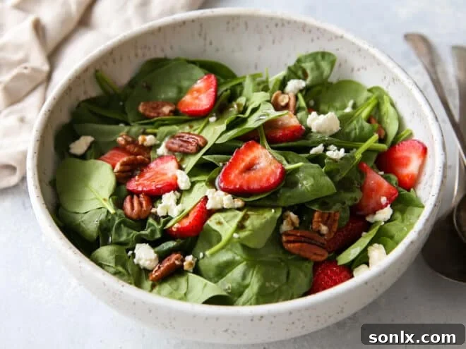 A vibrant strawberry spinach salad, tossed with the warm brown butter dressing and ready to be served, showcasing its colorful ingredients.