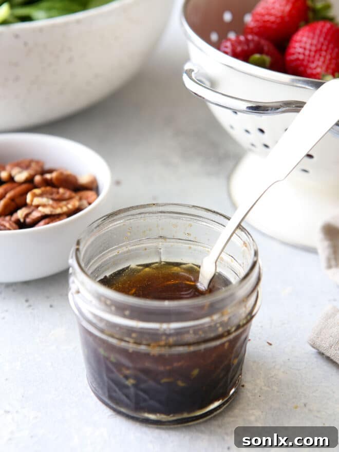A mason jar filled with warm, golden-brown butter dressing, ready to be poured over a salad.