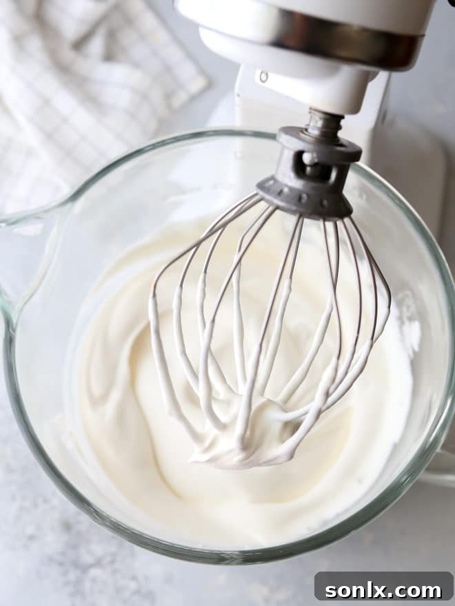 A hand mixer whipping cold heavy cream in a bowl, showing the initial stages of thickening.