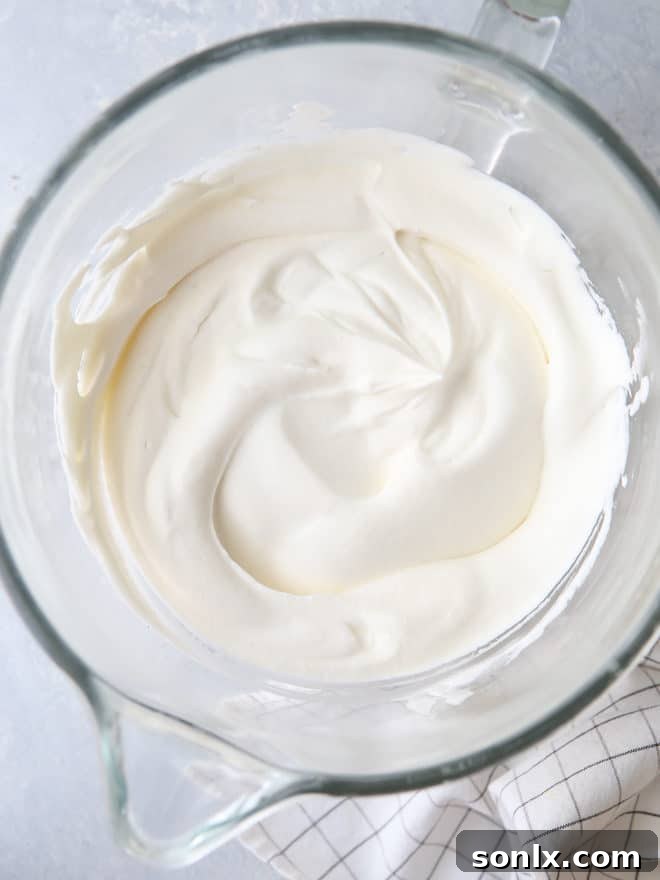A spoon scooping perfectly whipped cream from a bowl, showing its ideal texture.