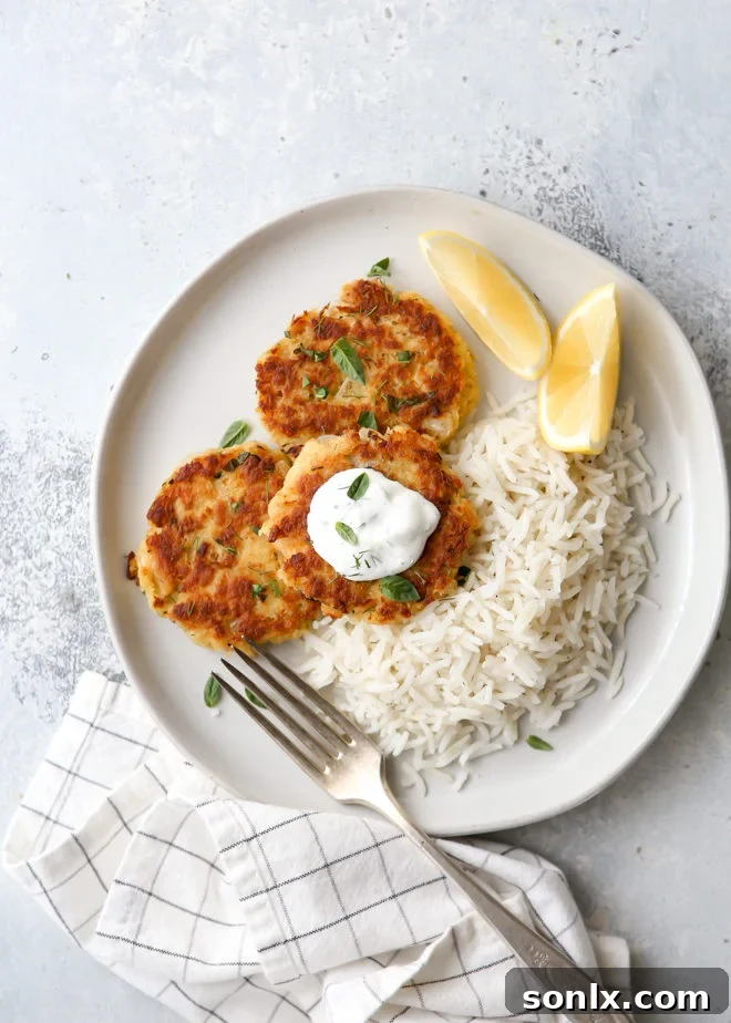 Golden-brown, crispy salmon patties served on a plate with lemon wedges and fresh herbs, ready to be enjoyed.