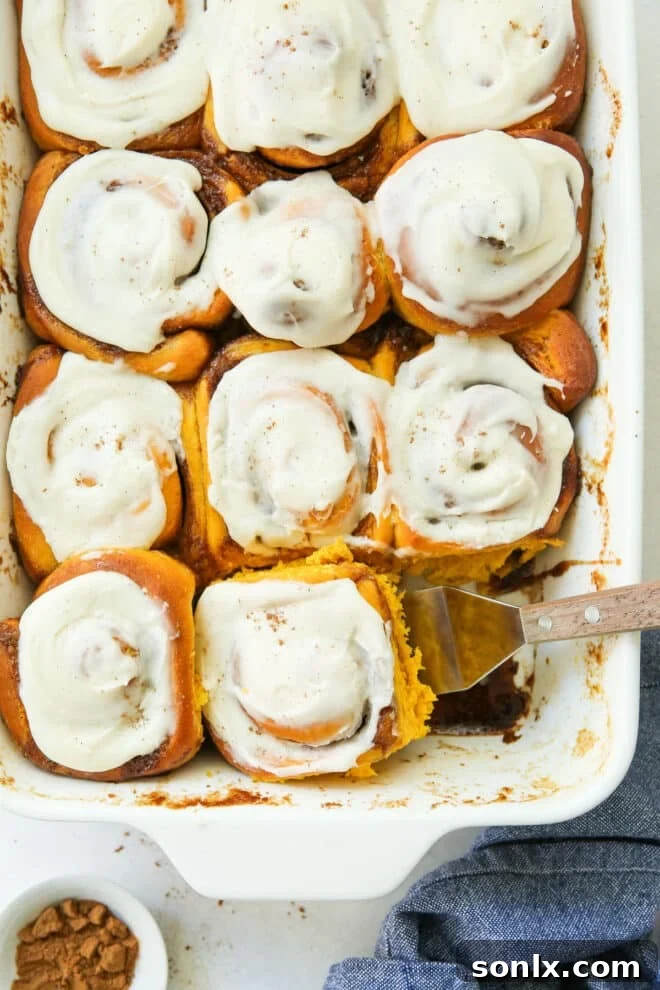 scooping pumpkin cinnamon rolls into a baking dish