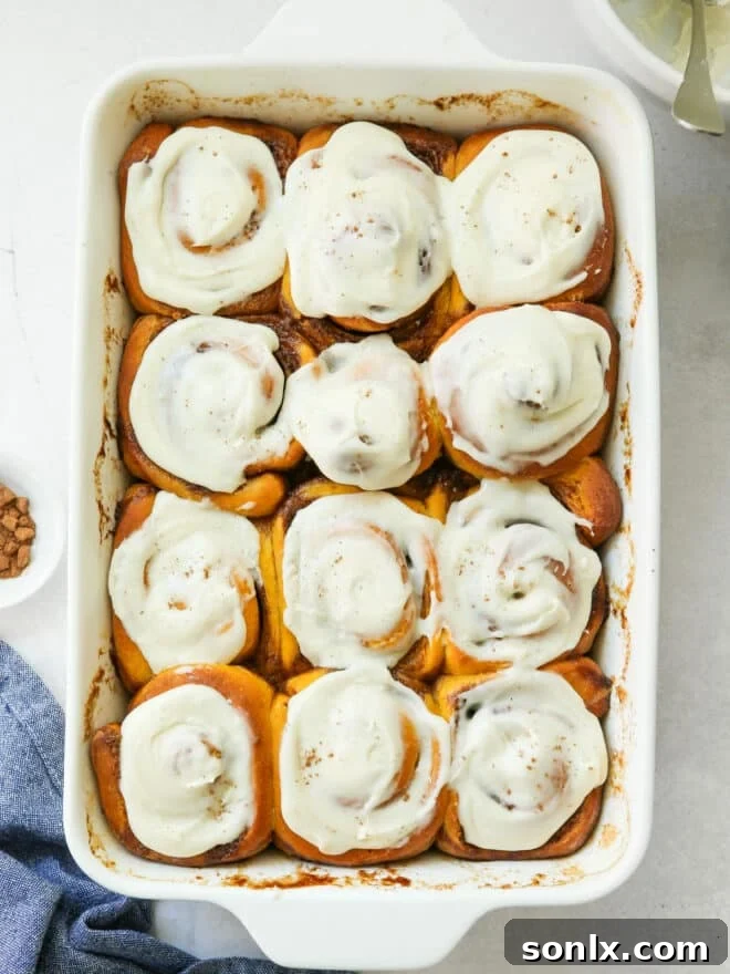 frosted pumpkin cinnamon rolls in baking pan