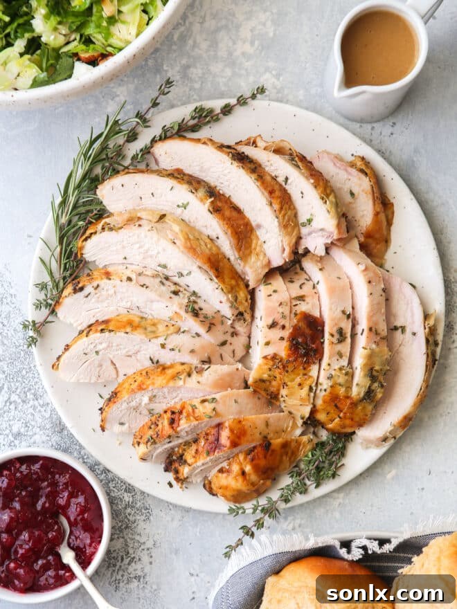 Sliced herb-roasted turkey breast arranged beautifully on a platter, accompanied by a fresh salad, vibrant cranberry sauce, rich homemade gravy, and fluffy dinner rolls.