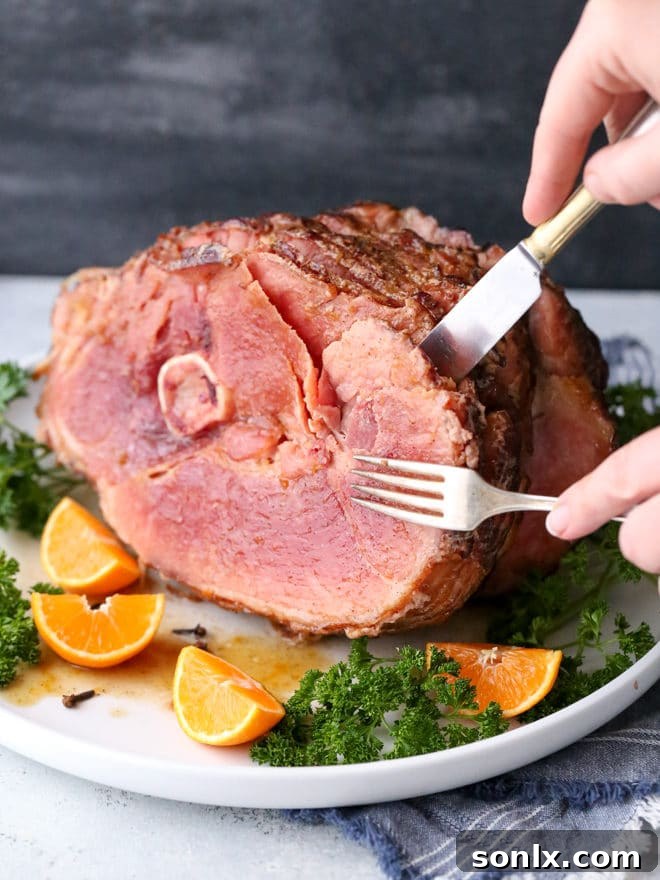 Close-up of the spiral ham being glazed with the homemade citrus spice mixture, showing its rich, amber color.
