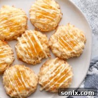 A close-up of a pineapple coconut macaroon with a golden brown bottom and a pineapple jam topping.
