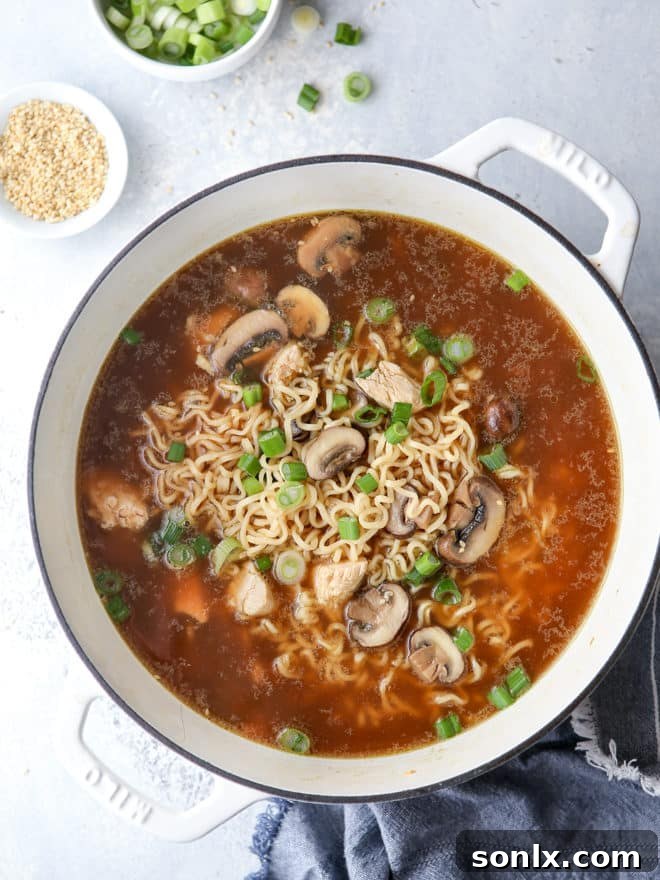 Close-up of the easy chicken ramen broth simmering with mushrooms, ginger, and garlic.