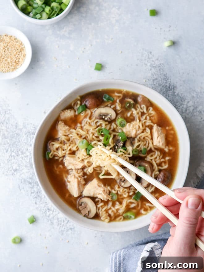 A delicious bowl of easy chicken ramen soup topped with scallions and sesame seeds, ready to be enjoyed.