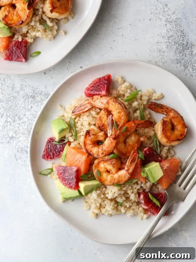 Citrus shrimp with vibrant oranges, creamy avocado, and fresh scallions over a bed of wholesome rice.