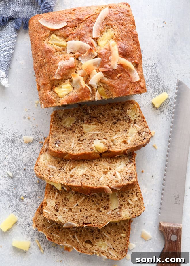A slice of lightened-up pineapple coconut bread on a plate, showing its moist texture and tropical ingredients.