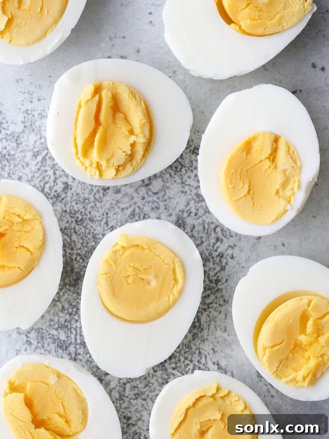 A bowl of freshly cooked, perfectly peeled hard-boiled eggs, showcasing their smooth, unblemished whites, ready for the next step in making delicious deviled eggs.