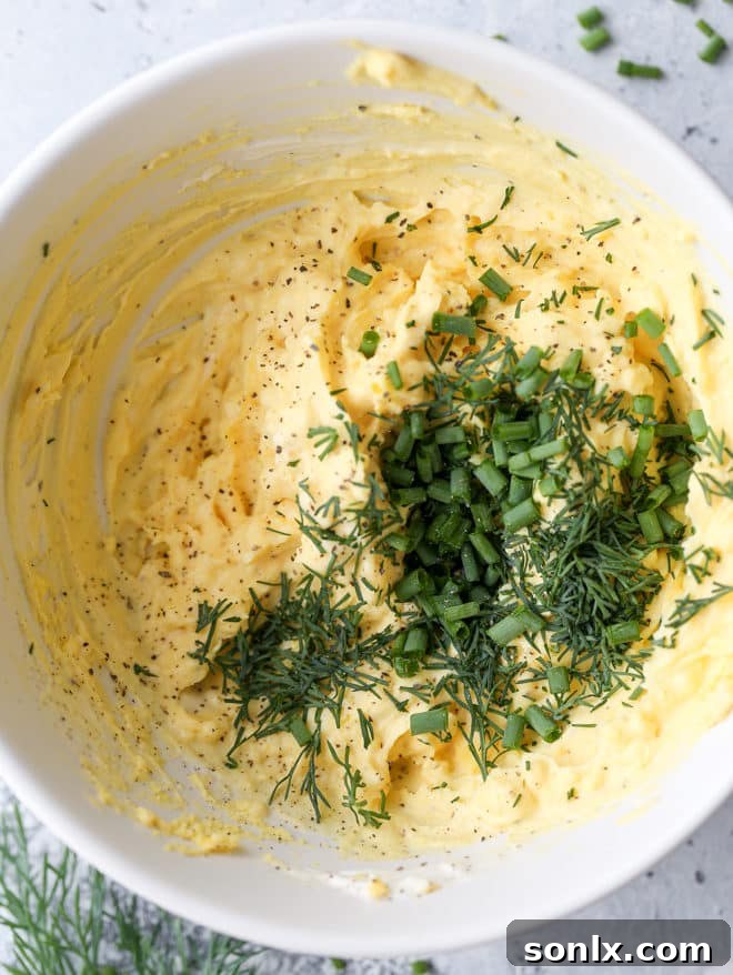 A vibrant platter of classic deviled eggs, showcasing their smooth, creamy filling and a sprinkle of fresh green herbs, ready to be enjoyed as a simple yet irresistible appetizer.