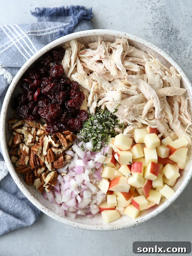 A serving of the chicken salad, garnished with fresh rosemary, ready to be enjoyed. The texture of the dressing and the visible ingredients are highlighted.