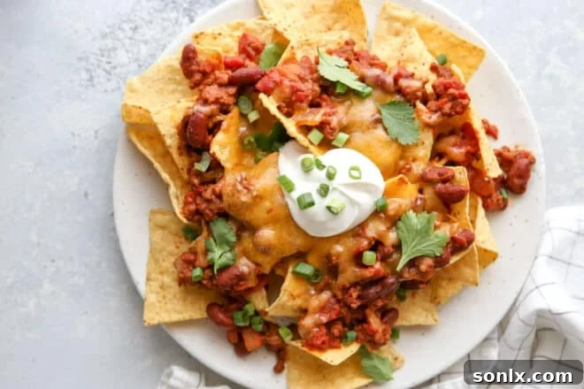 A large platter piled high with homemade chili cheese nachos, ready for serving.