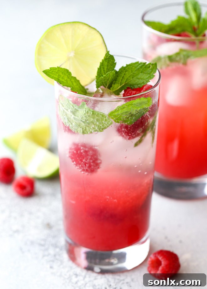 Refreshing Raspberry Mojito cocktail in a tall glass, garnished with fresh mint and raspberries, perfect for summer.