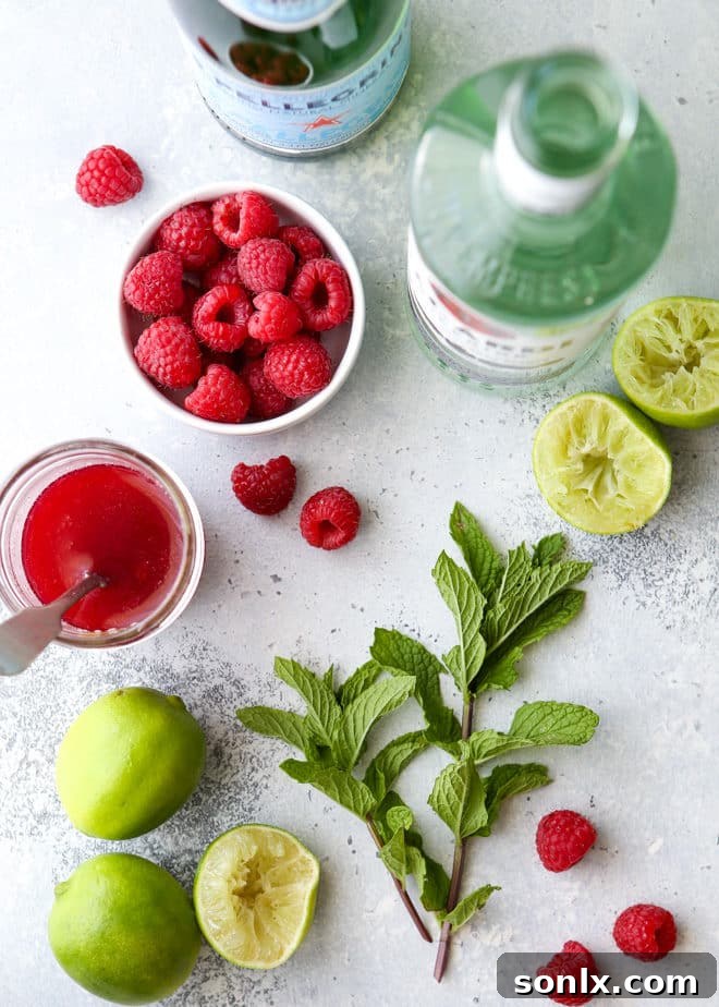 Close-up of a Raspberry Mojito being muddled with fresh mint leaves and lime, showing the vibrant ingredients.