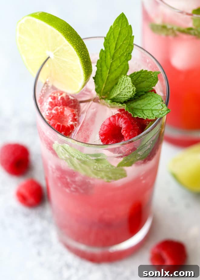 Three Raspberry Mojito cocktails on a wooden table outdoors, ready to be enjoyed on a warm summer evening.