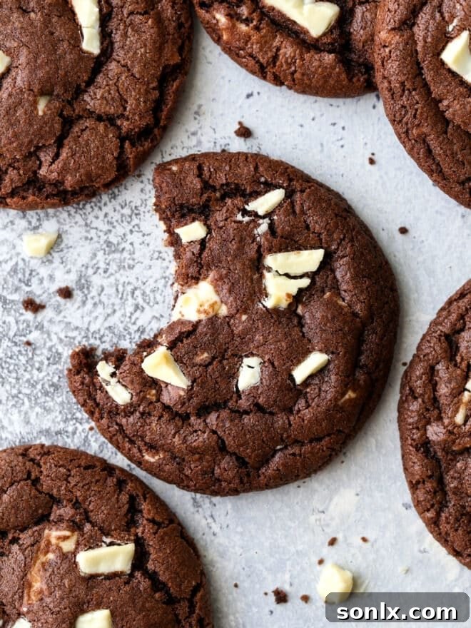 A perfectly baked chocolate cookie with visible white chocolate chunks, with a bite taken out to show its soft, fudgy interior.