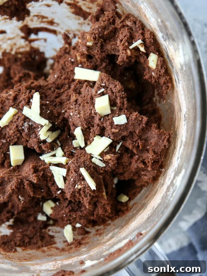 Close-up of chocolate cookie dough mixed with abundant white chocolate chunks, ready for baking.