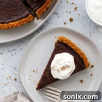 A delectable slice of dark chocolate tart with a gingersnap crust, presented elegantly on a plate.