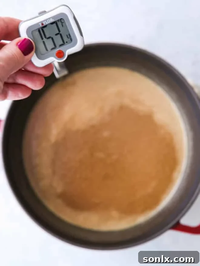 A candy thermometer immersed in a simmering pot of brown sugar mixture, showing the temperature reaching 238°F.