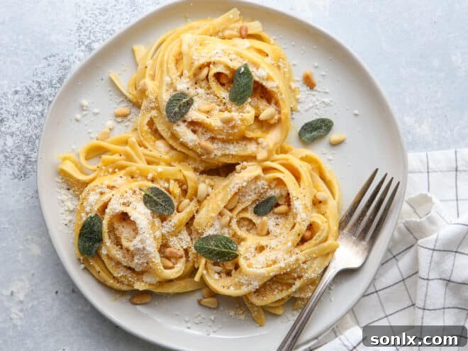 plated pumpkin alfredo pasta with garnishes on a plate with fork