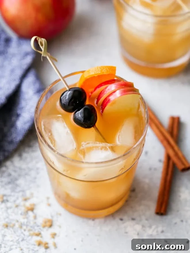 closeup of apple cider old fashioned in a glass with garnishes