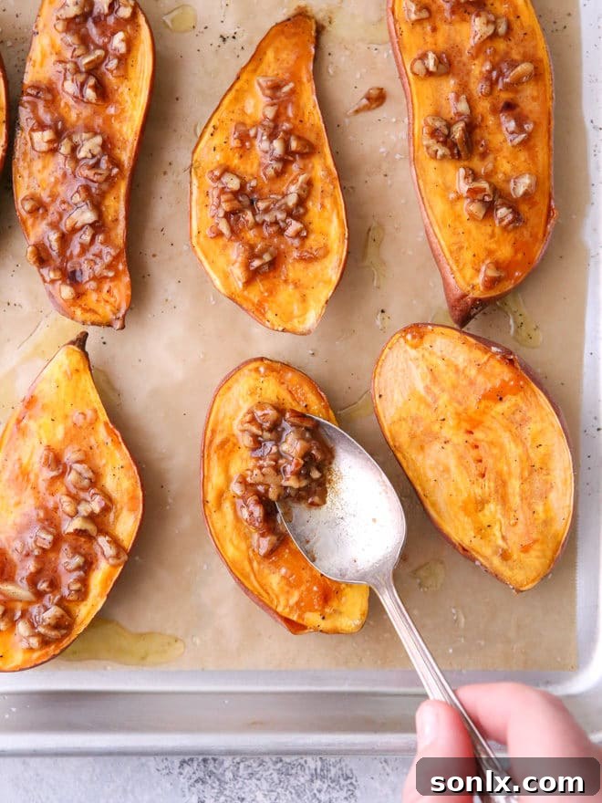 Maple pecan sauce being spooned over roasted sweet potatoes before their final bake.
