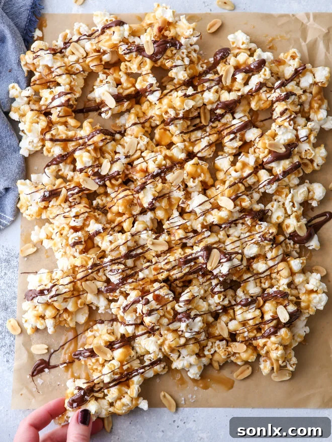 A large batch of chocolate caramel corn spread out on parchment paper, ready to be enjoyed.