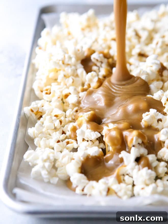 Hands stirring a large bowl of caramel-covered popcorn, showing the gooey texture.