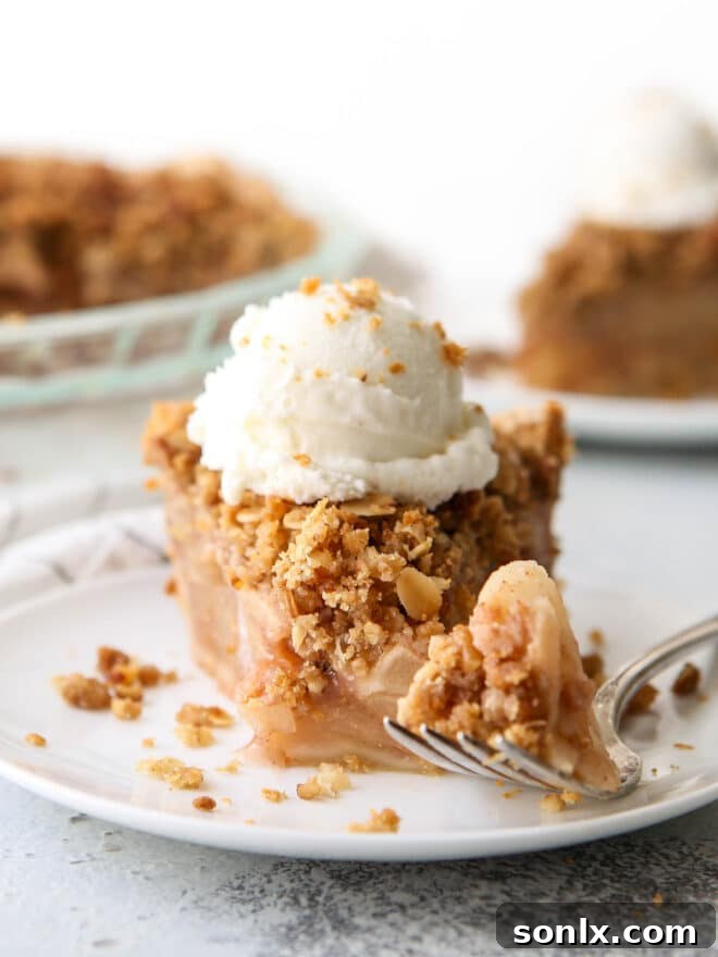 A tantalizing slice of apple crumble pie on a plate, with a fork holding a bite-sized piece, highlighting the crisp topping and tender filling.