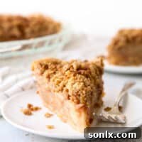 A tantalizing slice of apple crumble pie on a plate, showcasing its golden topping and rich filling.
