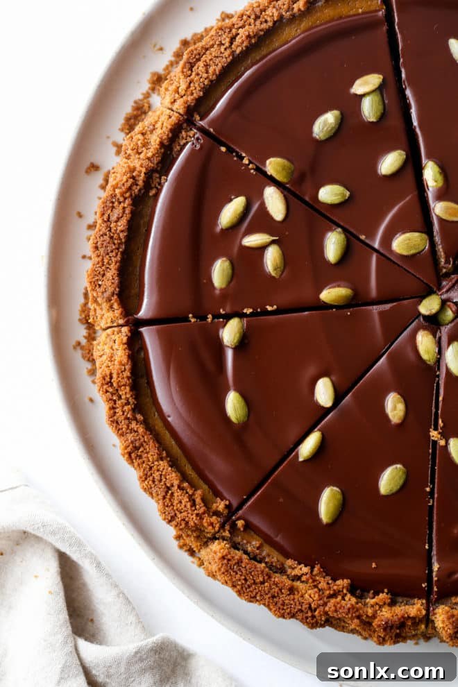 A beautifully sliced chocolate pumpkin tart, showing off its distinct layers of crust, filling, and ganache.