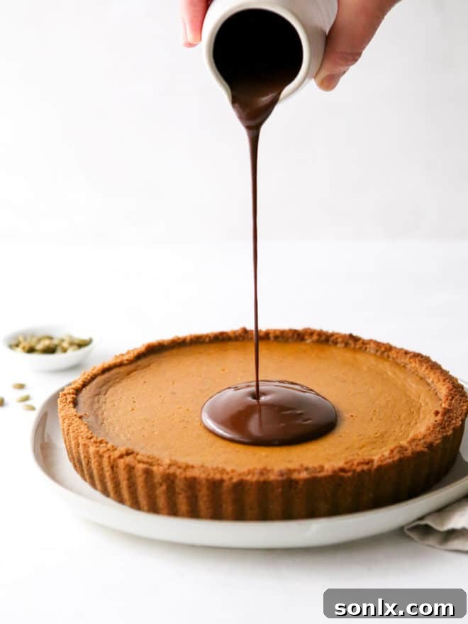 Pouring rich, dark chocolate ganache over a freshly baked pumpkin tart.