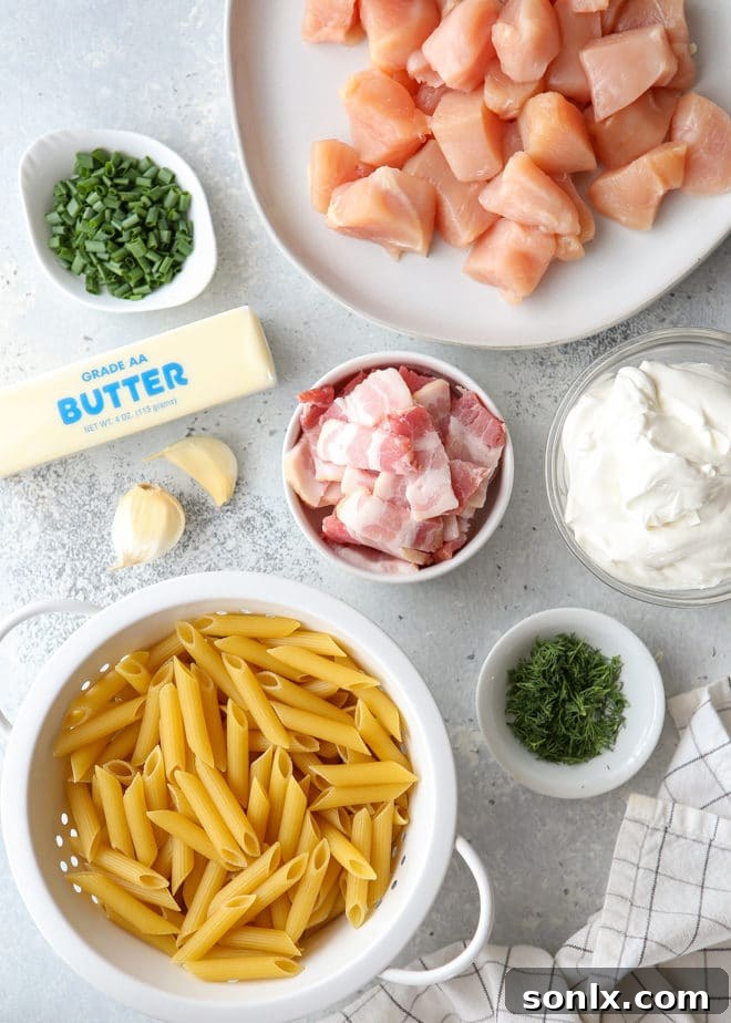 Close-up of the ingredients for chicken bacon ranch pasta, including penne, chicken breast, bacon, and fresh herbs.