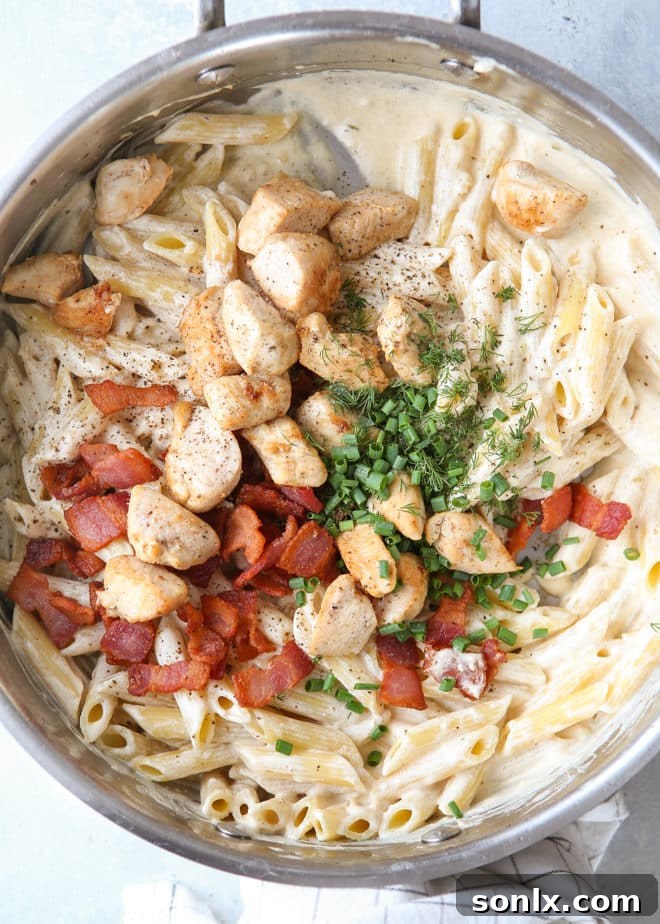 A serving of chicken bacon ranch pasta in a bowl, garnished with fresh herbs, ready to be enjoyed.