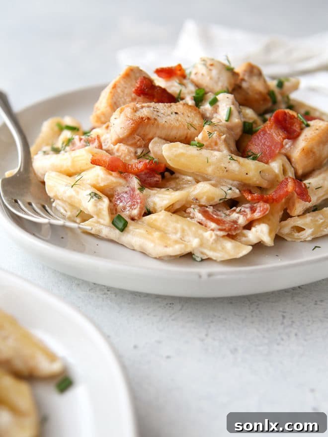 A large platter of chicken bacon ranch pasta, garnished with fresh herbs, ready for serving.