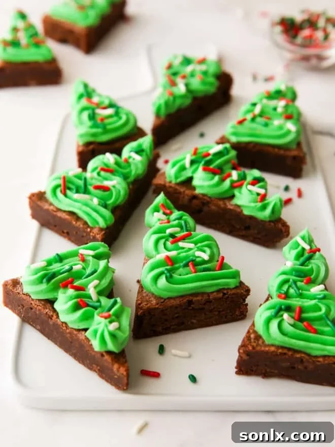 A top-down view of a tray of freshly baked brownies, some already cut into festive Christmas tree shapes.