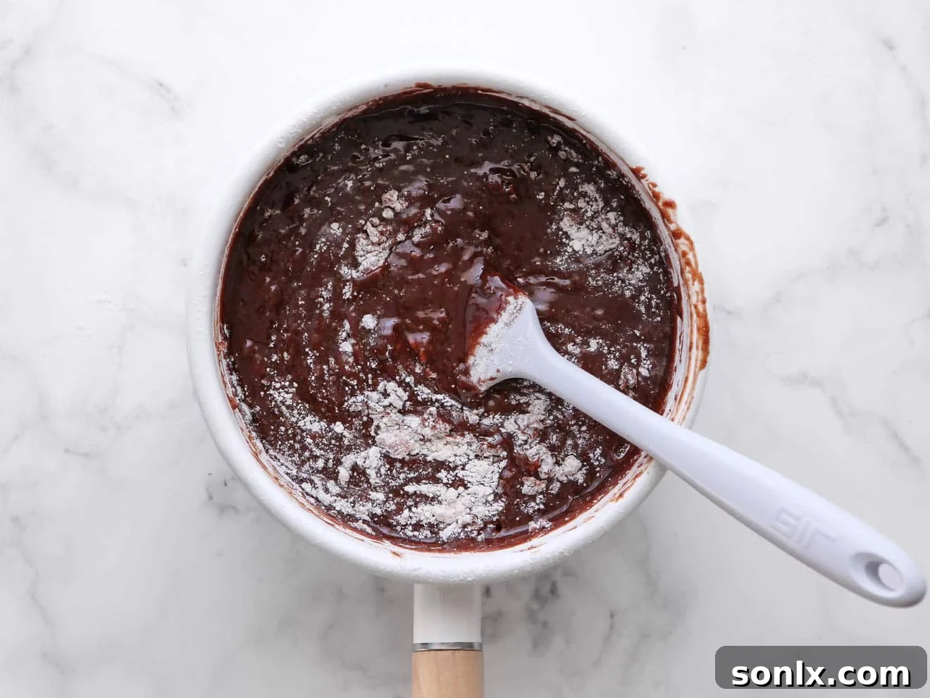 Step-by-step image showing the brownie batter being mixed in a bowl with melted chocolate and butter.