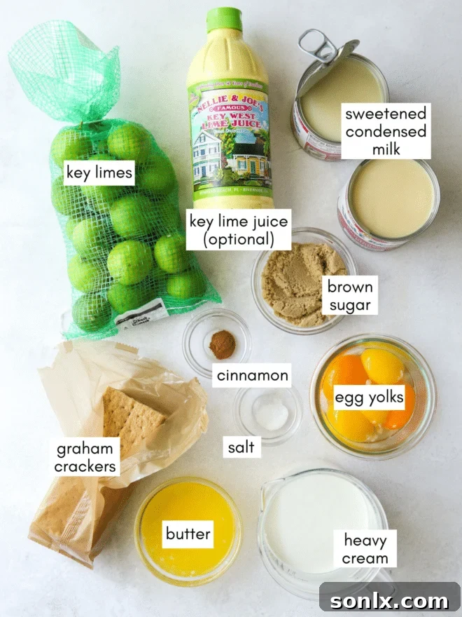 Various ingredients for key lime pie laid out on a table, including graham crackers, limes, condensed milk, and heavy cream.