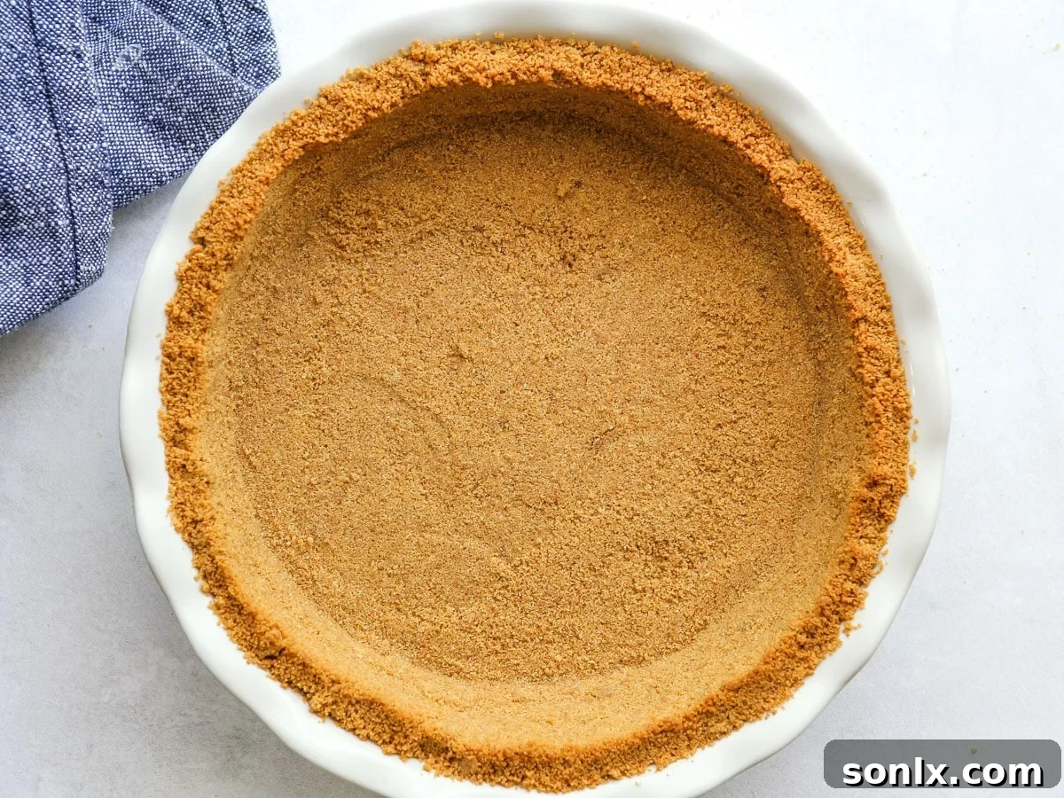 Graham cracker crust pressed firmly into a pie pan, ready for baking.