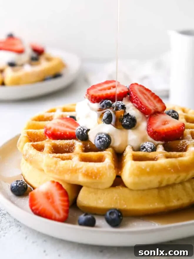 close-up shot of a stack of fluffy buttermilk waffles, lightly drizzled with golden syrup