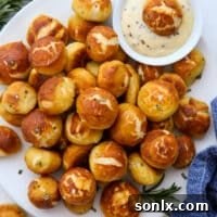 Cheddar rosemary pretzel bites on a plate with honey mustard dipping sauce.