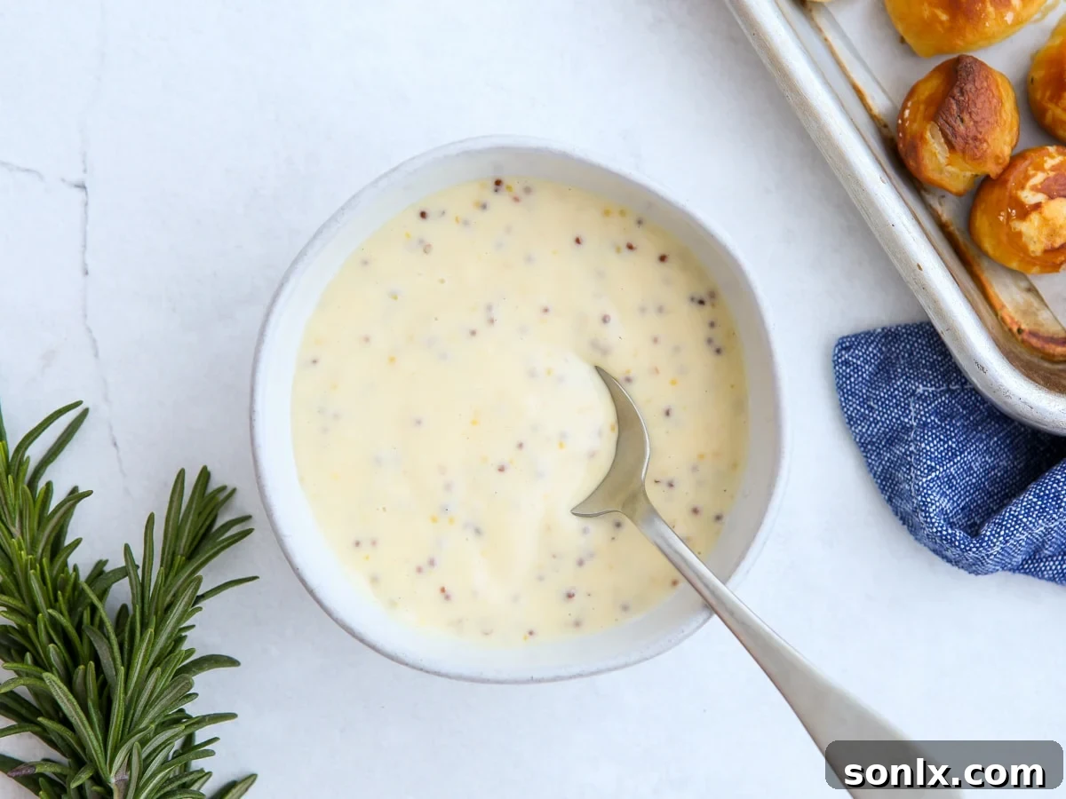 A bowl of creamy honey mustard sauce, ready for dipping, with a whisk nearby.