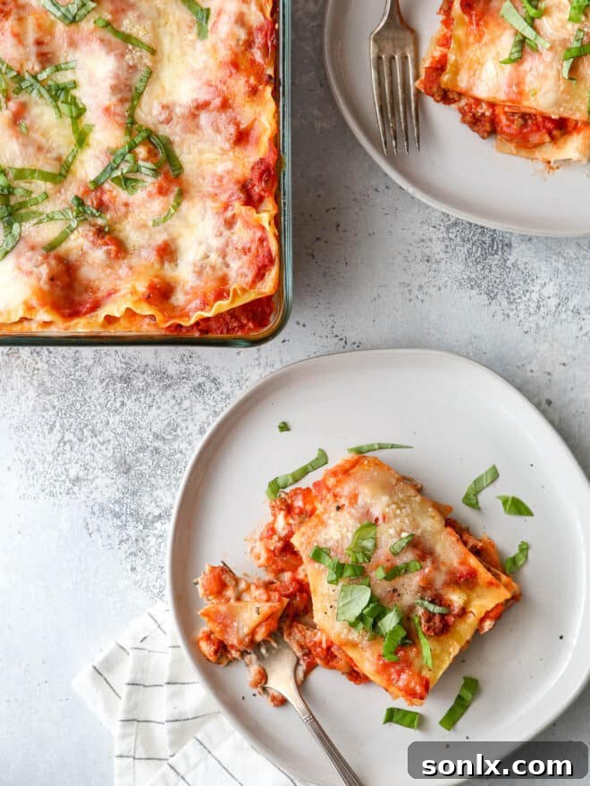 Close-up of a fork with a perfect bite of classic homemade lasagna, showing melted cheese and meat sauce.