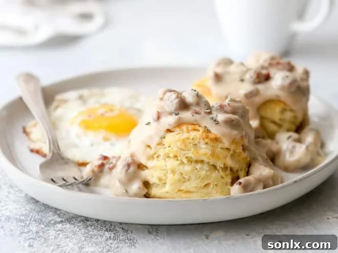 a plate of biscuits and gravy with fried egg in background